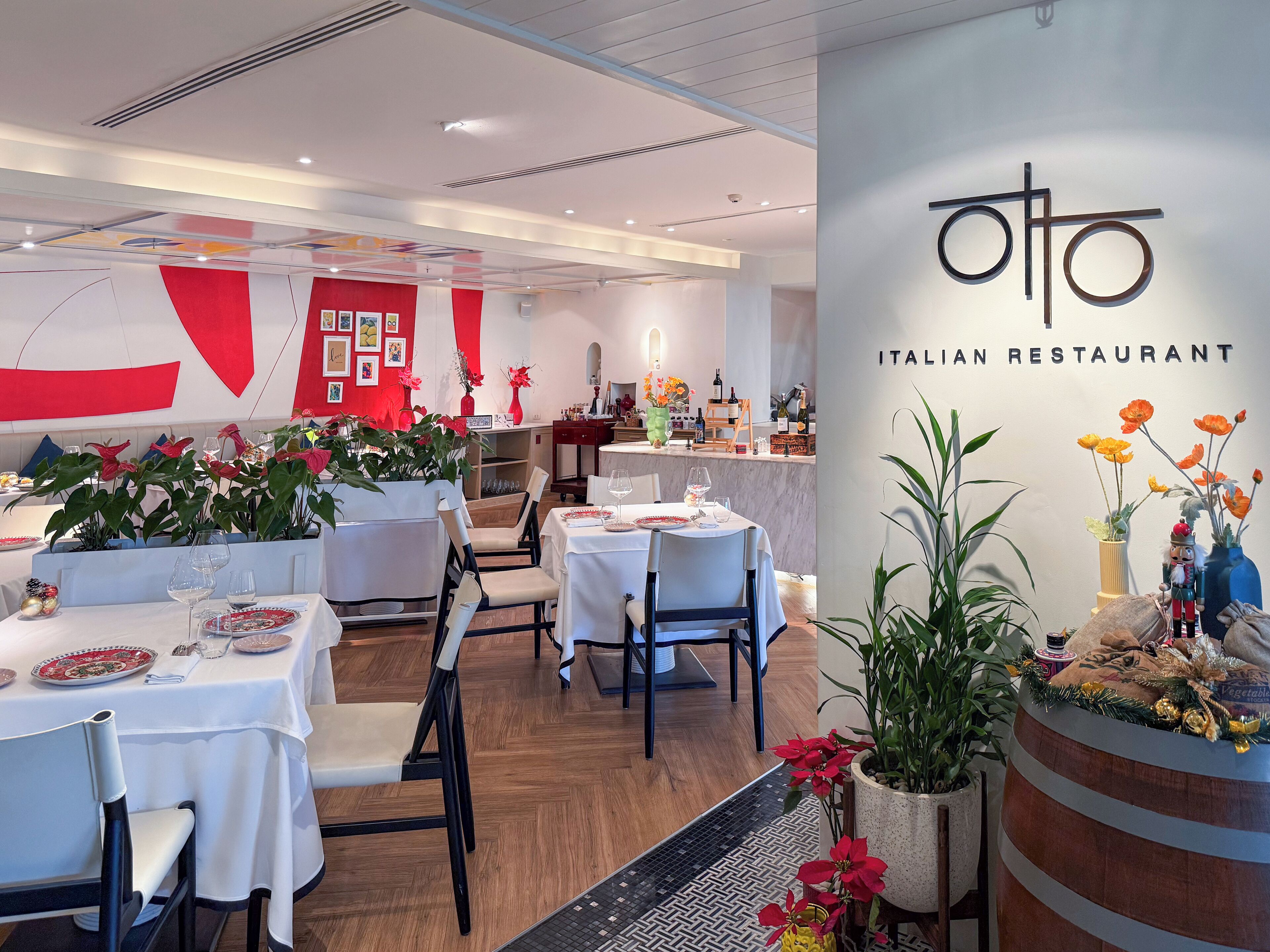 An Italian restaurant with tables set for dining, a bar area, and decorative plants.