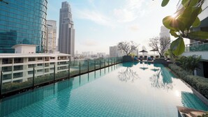 A rooftop infinity pool with a cityscape view, surrounded by modern buildings and greenery. - MUU Bangkok, Small Luxury Hotels of the World (Bangkok)