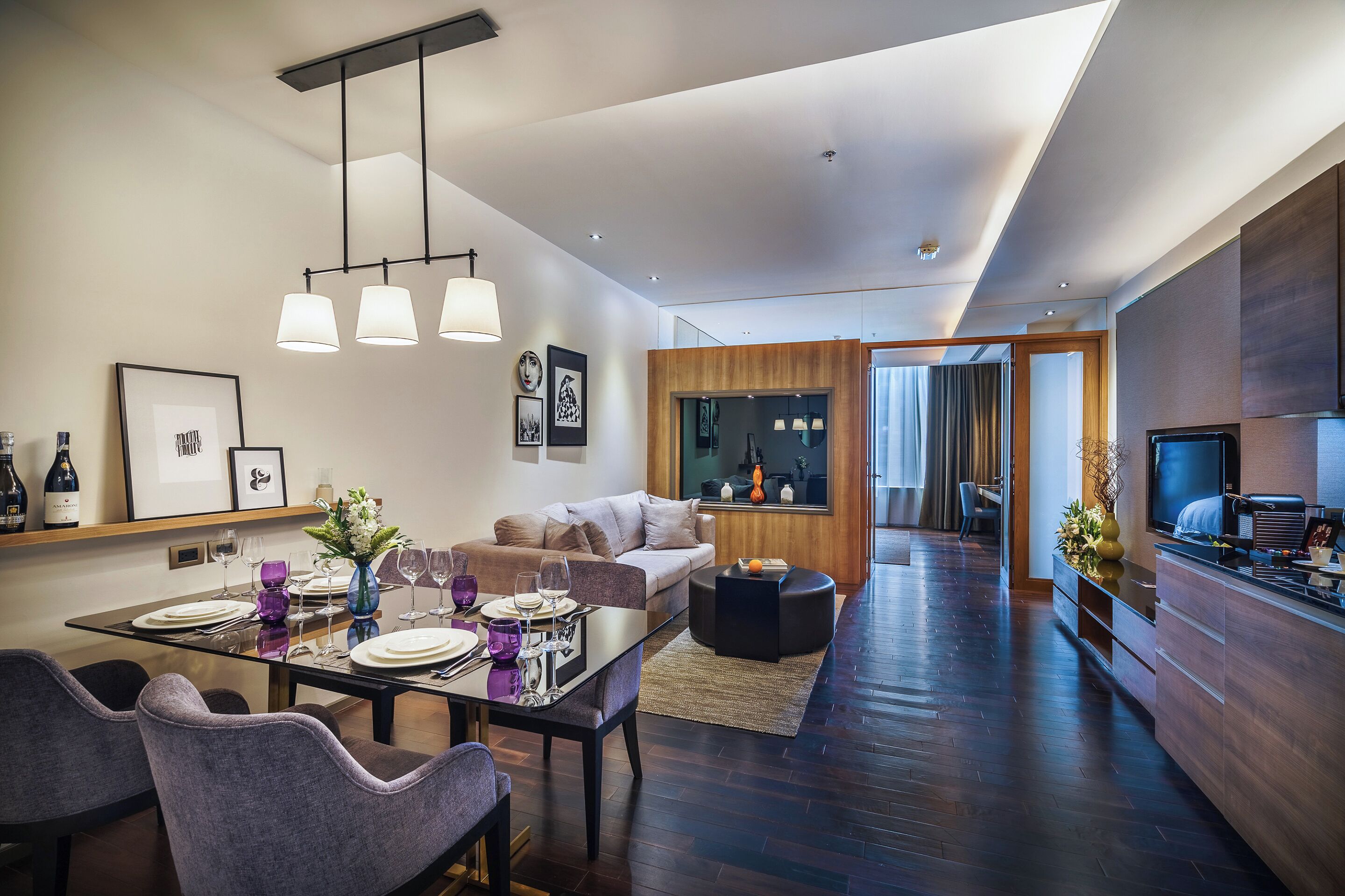 A modern living room with a dining area, featuring a sofa, a coffee table, and a TV.