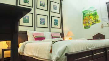 A hotel room with a bed, a nightstand, a lamp, and a wall with framed pictures.