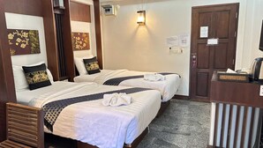 A hotel room with two beds, a wooden headboard, a small desk with a kettle, and a wall-mounted light fixture. - Sunday Rainforest Chiangmai Hotel  (Chiang Mai)