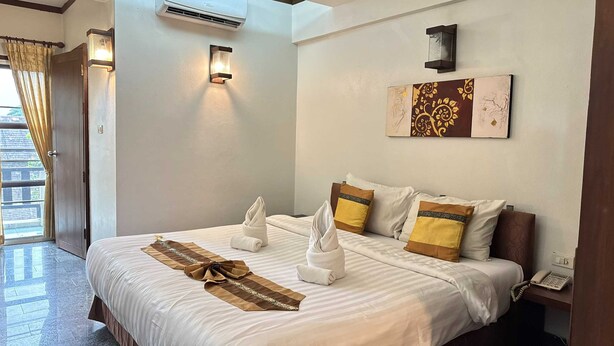 A hotel room with a bed, a telephone, and a wall-mounted artwork. - Sunday Rainforest Chiangmai Hotel  (Chiang Mai)