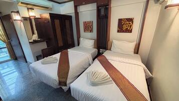 A hotel room with two beds, a mirror, a door, and a wall-mounted air conditioner.