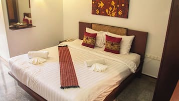 A hotel room with a neatly made bed, a bedside table with a lamp, and a painting on the wall.
