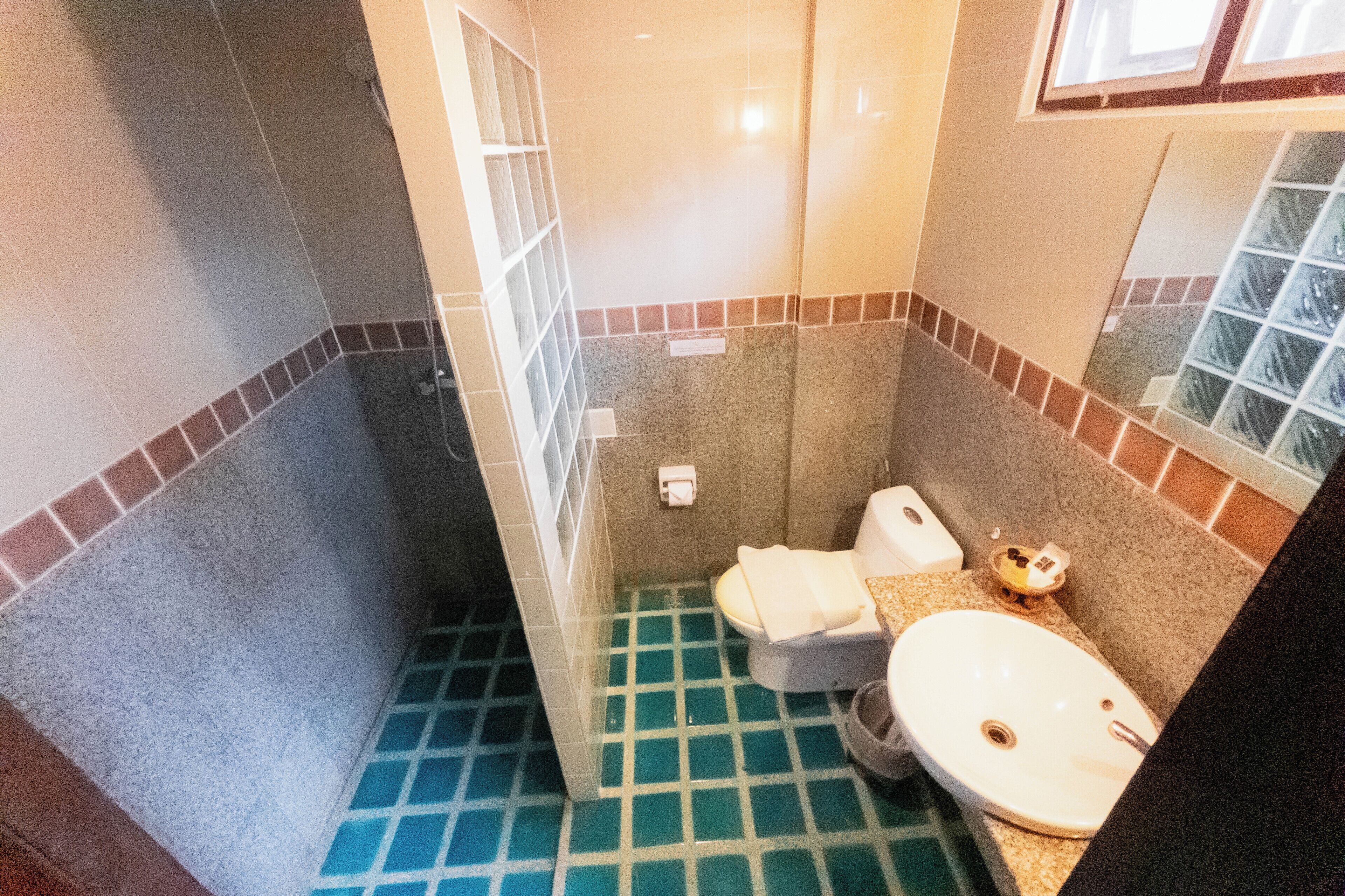 Ein Badezimmer mit gefliestem Boden, Toilette, Waschbecken und Spiegel.