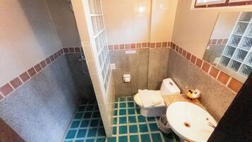 Ein Badezimmer mit gefliestem Boden, Toilette, Waschbecken und Spiegel.