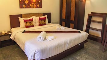 A hotel room with a large bed, a nightstand with a phone, a wall-mounted artwork, and a wooden door.