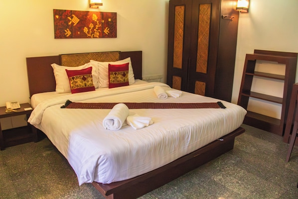 Habitación de hotel con una cama grande, una mesita de noche con teléfono, una obra de arte en la pared y una puerta de madera.