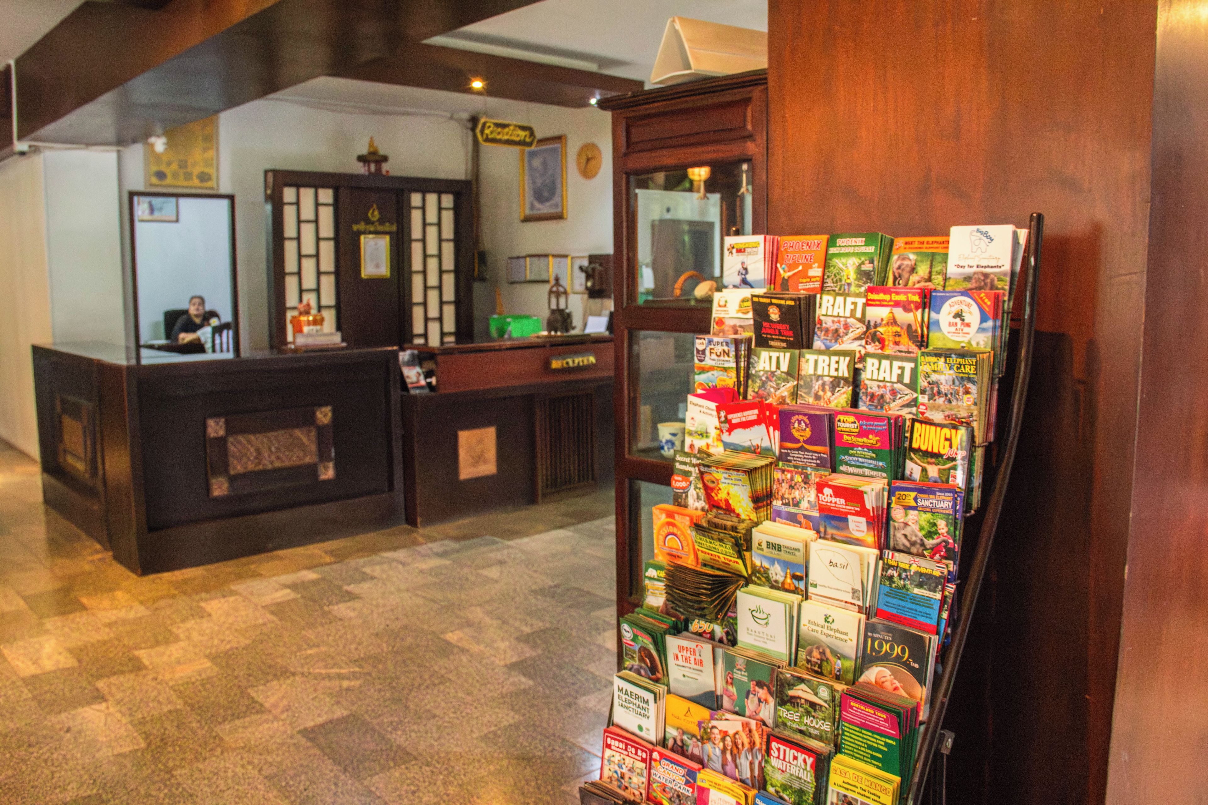 A reception desk with a magazine rack filled with travel and adventure books.