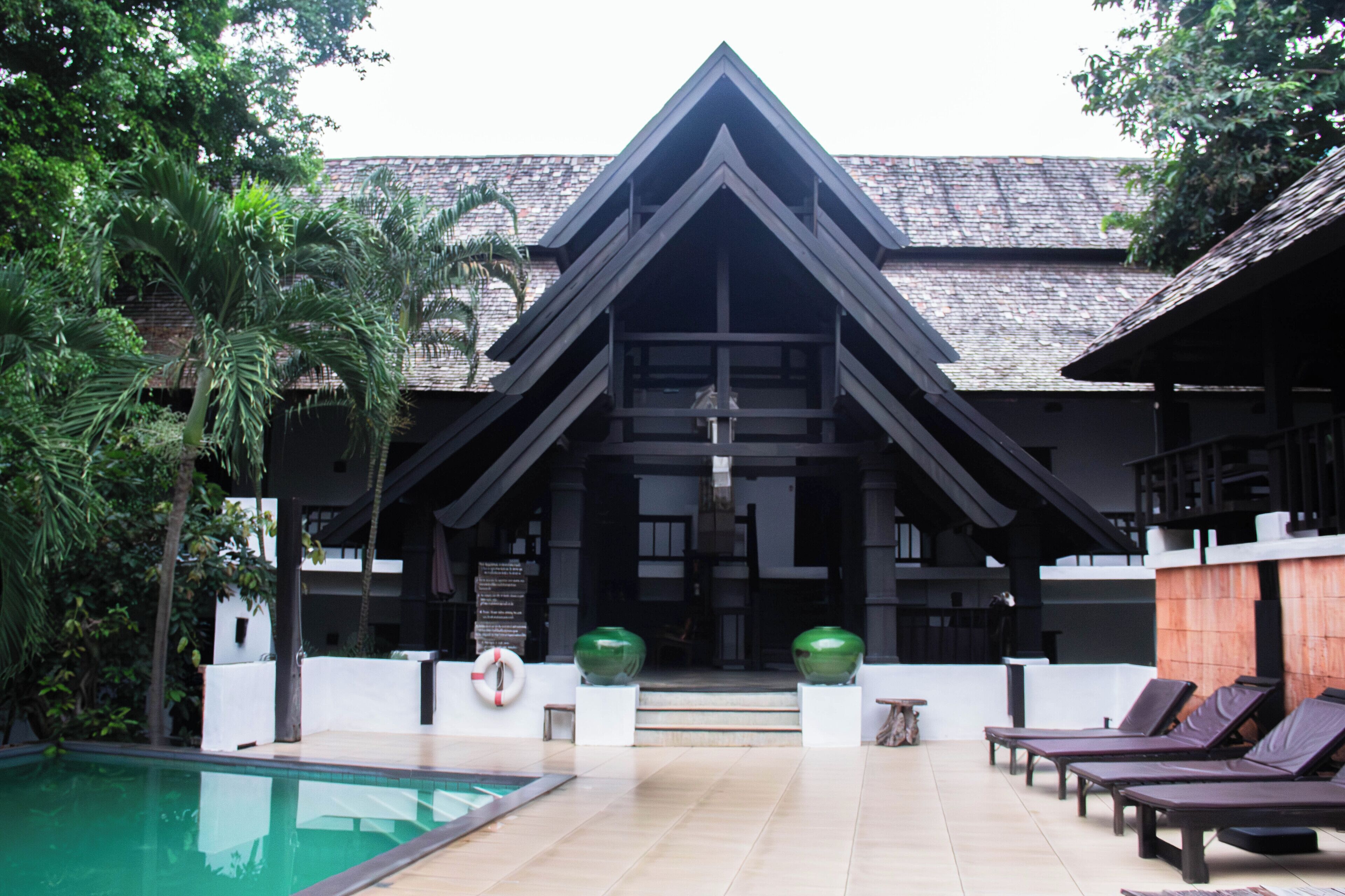 A resort with a swimming pool, lounge chairs, and a building with a distinctive triangular roof.