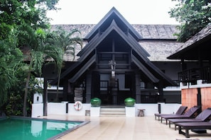 A resort with a swimming pool, lounge chairs, and a building with a distinctive triangular roof. - Sunday Rainforest Chiangmai Hotel  (Chiang Mai)