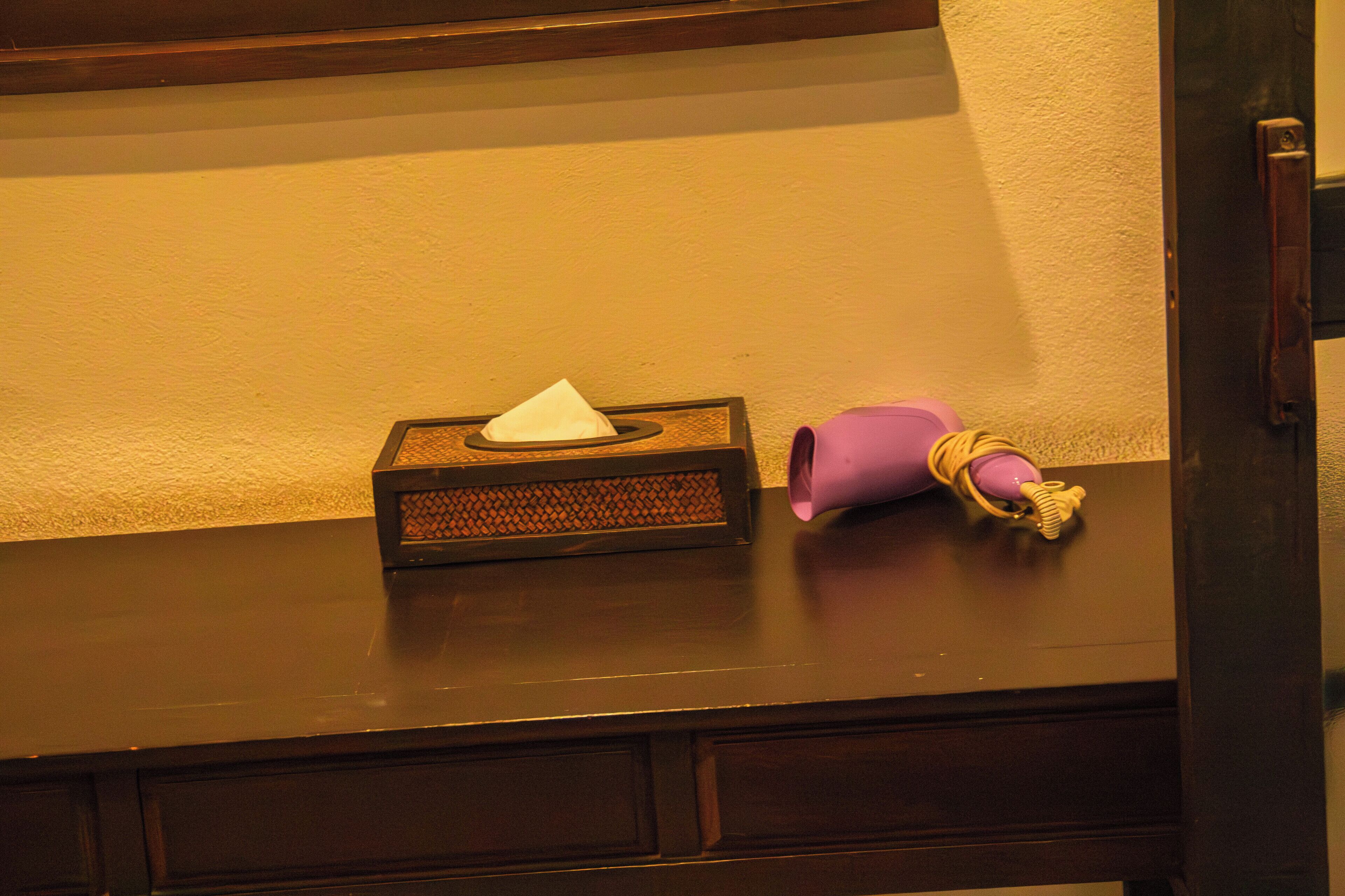 A tissue box and a purple object on a dark wooden surface.