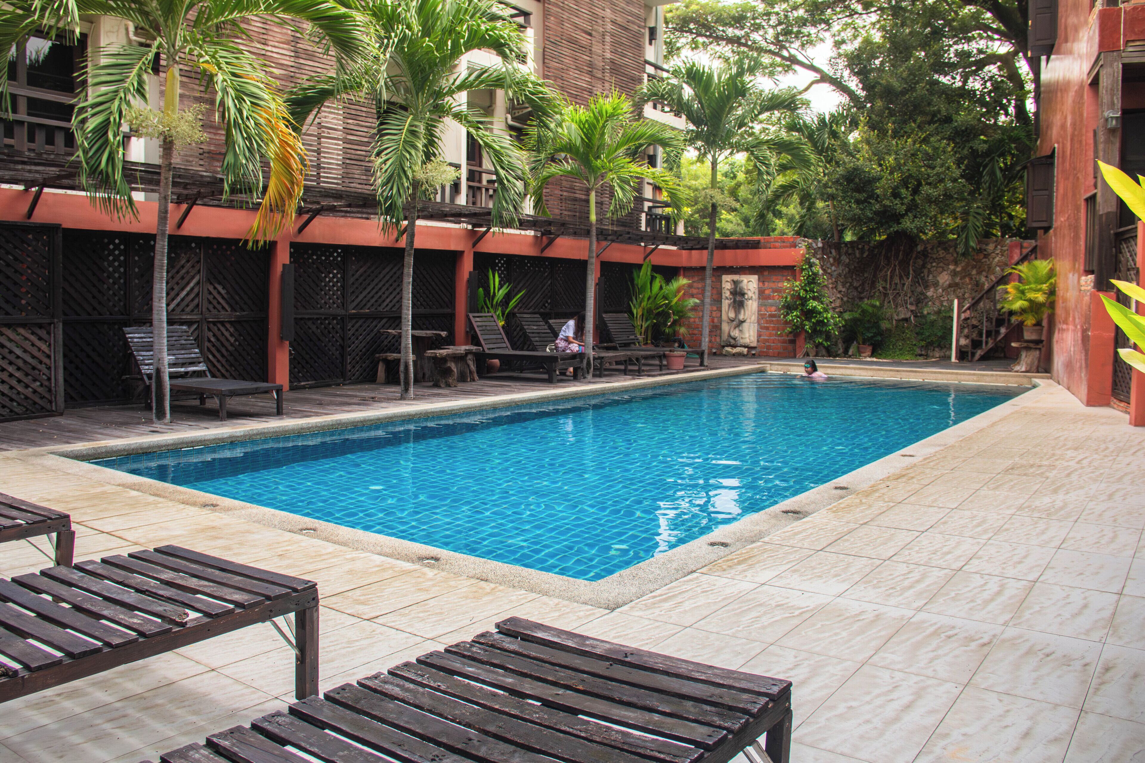 A swimming pool with lounge chairs and palm trees.