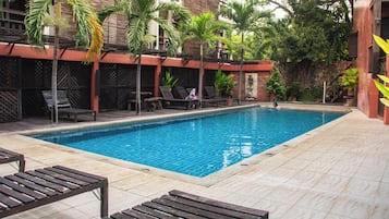 A swimming pool with lounge chairs and palm trees.