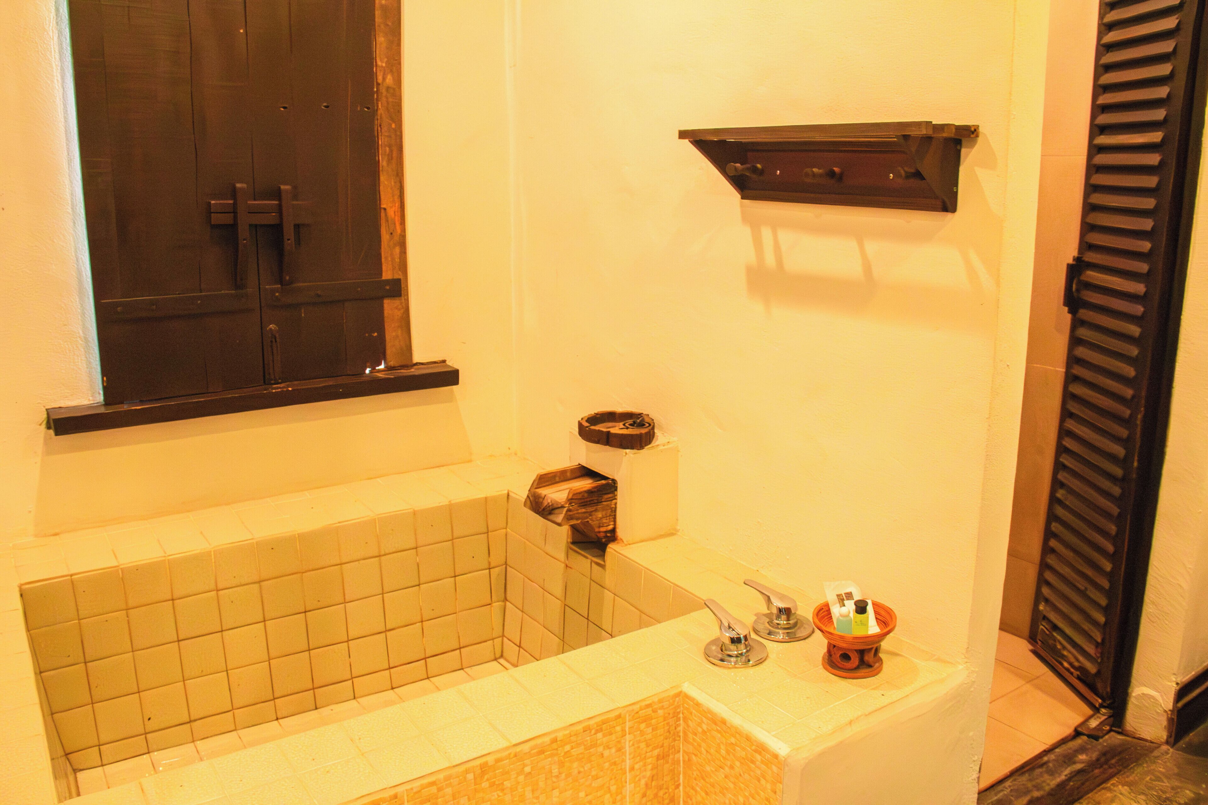 A bathroom with a bathtub, a window, a towel rack, and a shelf.