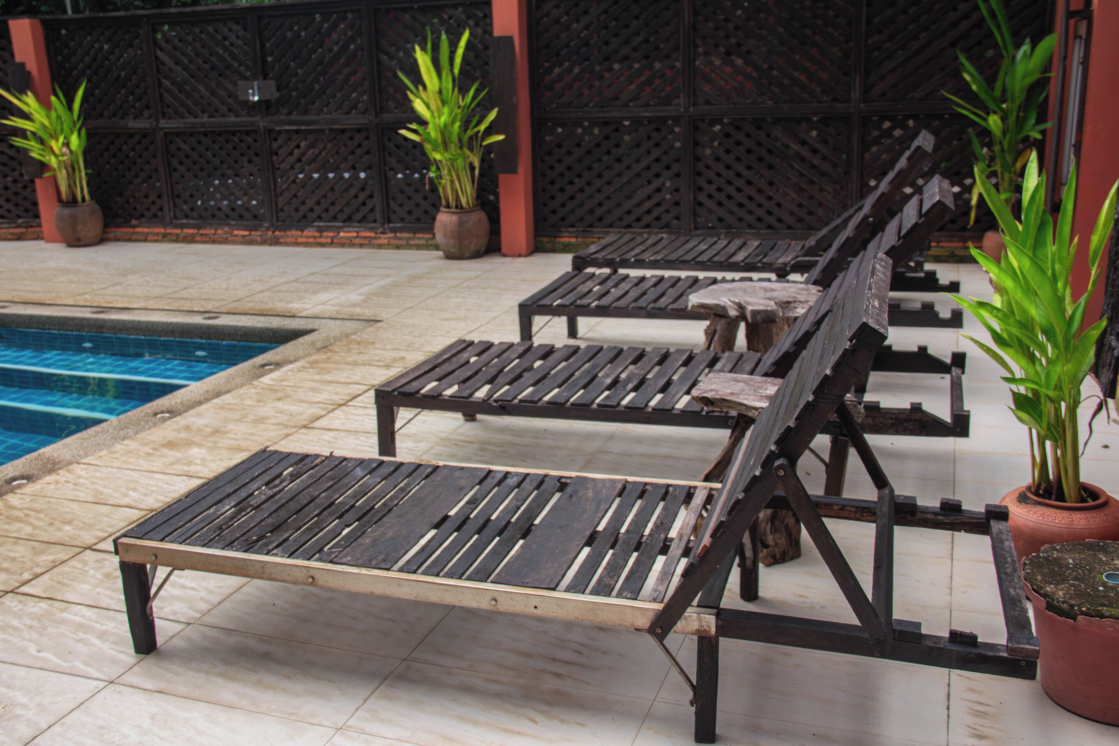 A poolside area with lounge chairs and potted plants.