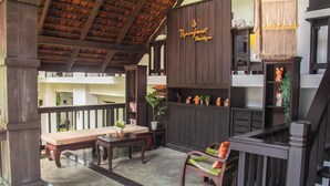 A wooden interior with a bench, a table, and a chair. There is a sign that reads 'Rainforest Boutique'. - Sunday Rainforest Chiangmai Hotel  (Chiang Mai)