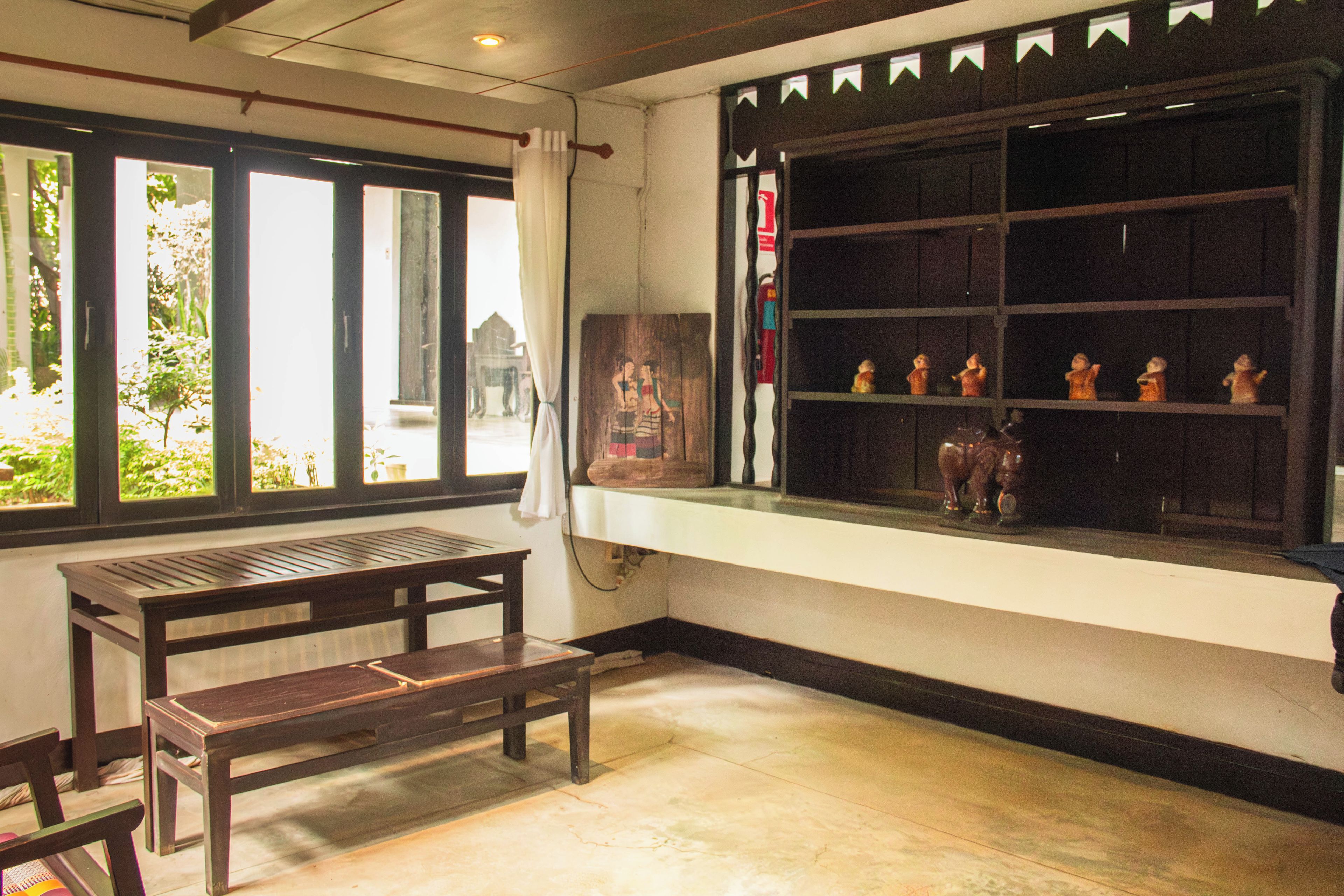 A room with a wooden bench, a window with decorative elements, and a shelf with figurines.