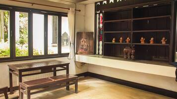 A room with a wooden bench, a window with decorative elements, and a shelf with figurines.