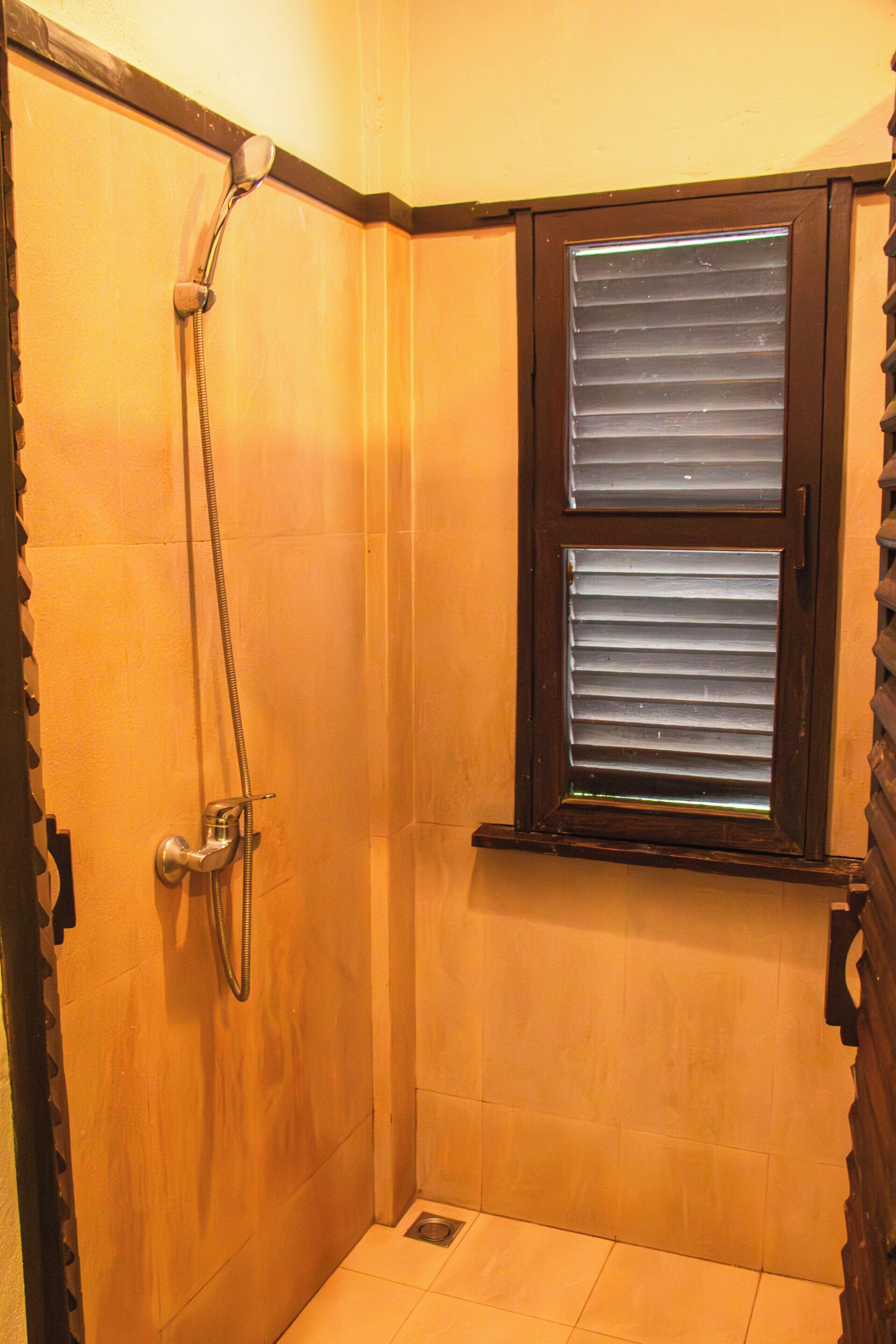 A small, enclosed shower area with a window, a showerhead, and a door.
