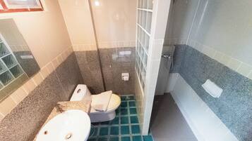 A bathroom with a toilet, sink, and shower area.
