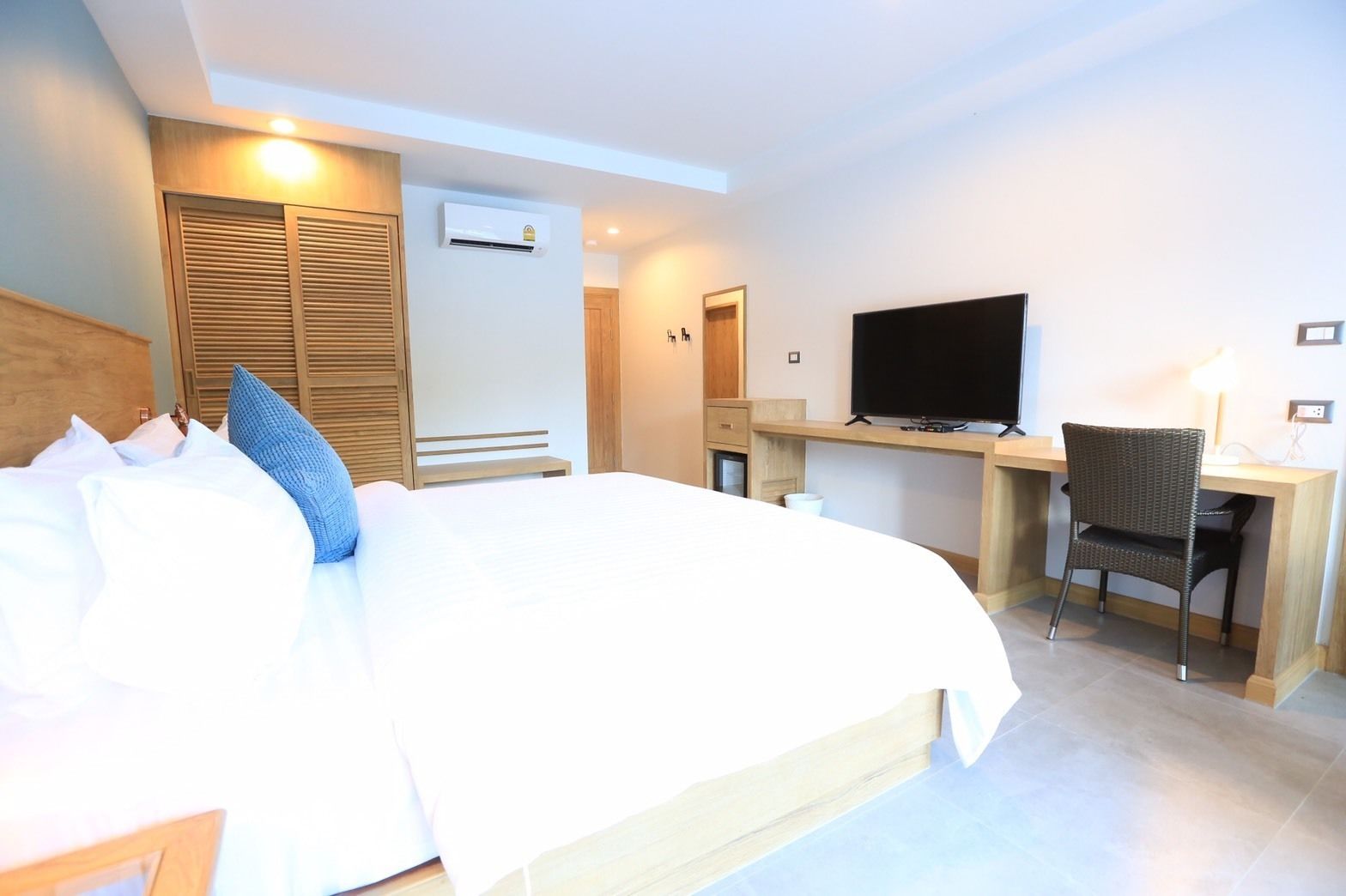 Ett hotellrum med en säng, ett skrivbord, en tv och en stol.