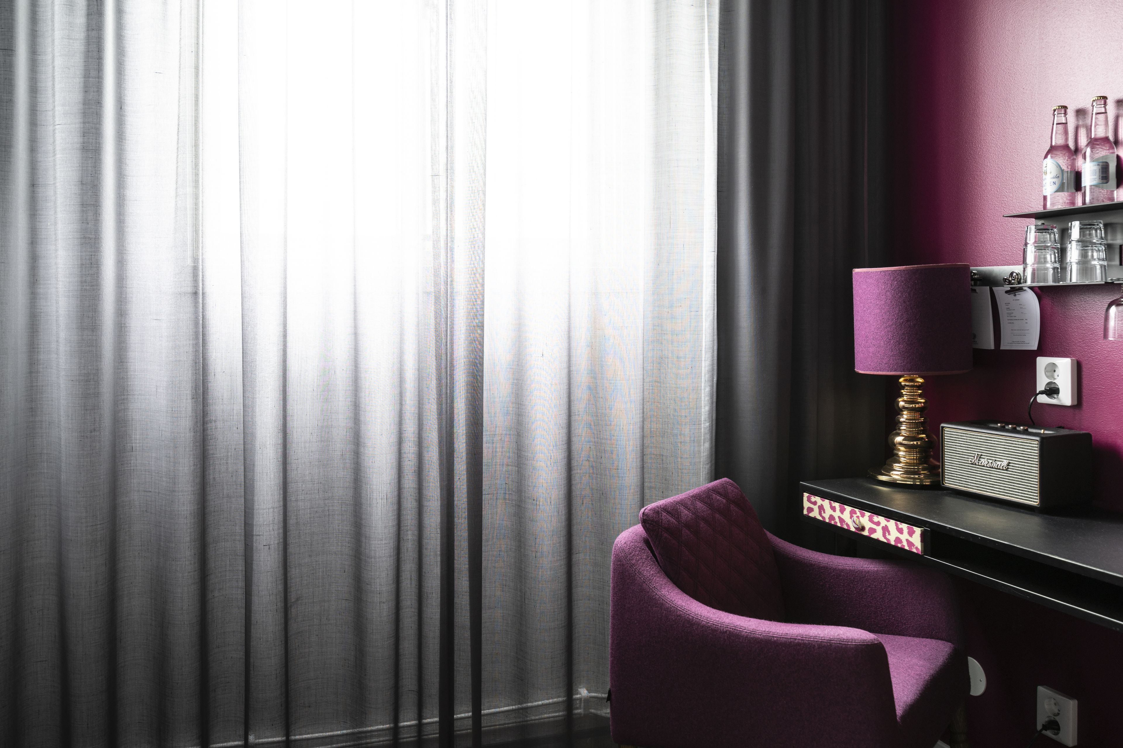 A room with a purple chair, a radio, and a shelf with bottles.