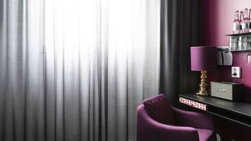A room with a purple chair, a radio, and a shelf with bottles.