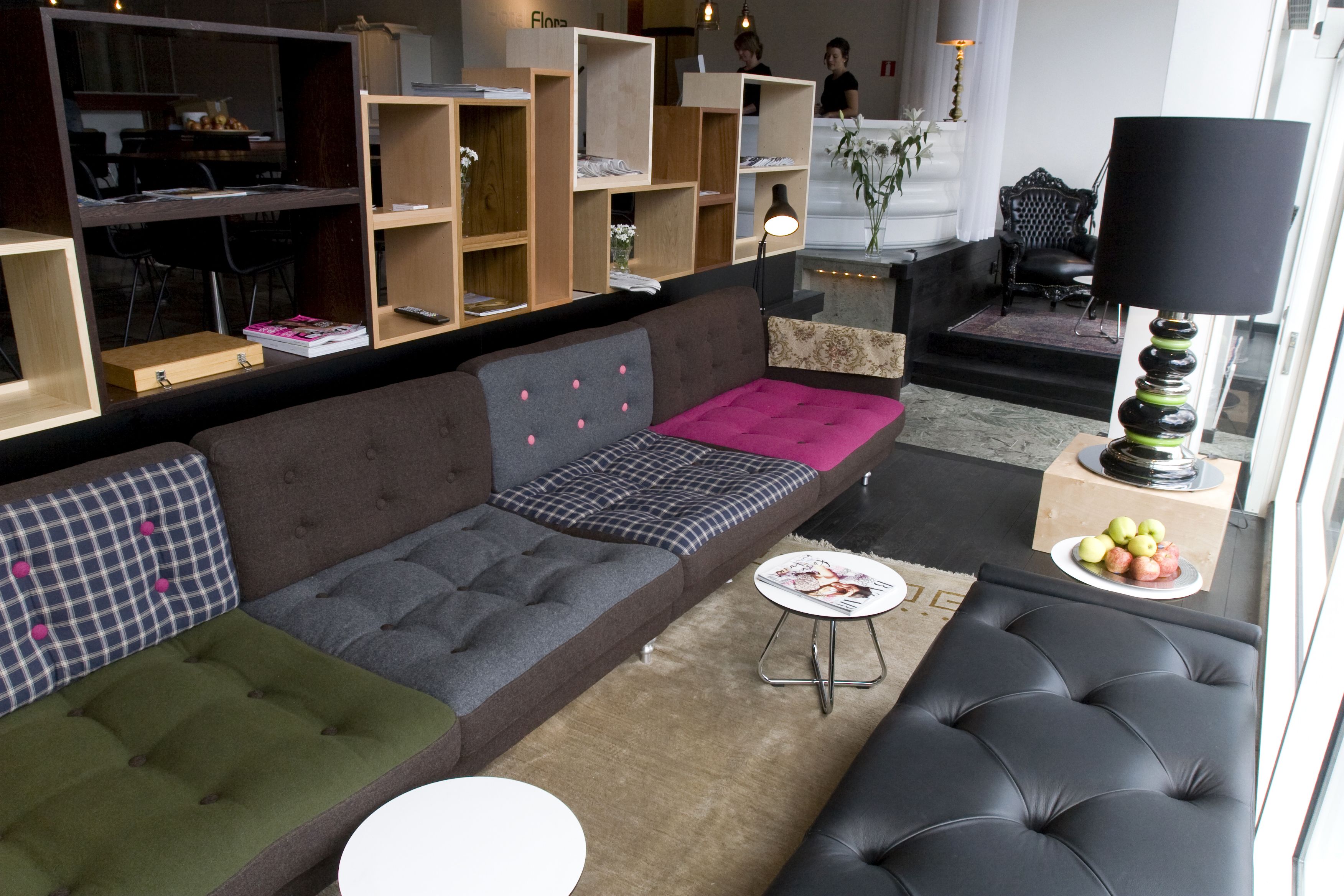 A modern living room with a sectional sofa, a small round table, and built-in wooden shelving.