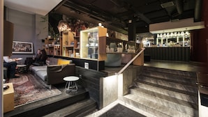 A modern interior with a reception desk, a staircase, and seating areas. - Hotel Flora (Gothenburg)