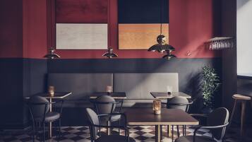 A modern restaurant with checkered flooring, dark and red walls, and a variety of seating options including booths and tables.