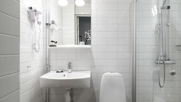 Un baño moderno con lavamanos, inodoro y cabina de ducha de vidrio.