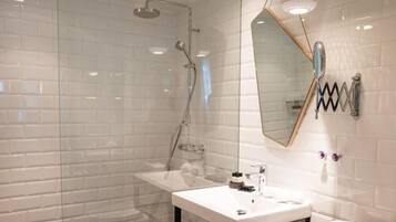 A modern bathroom with a glass-enclosed shower, a white sink, and a large mirror.