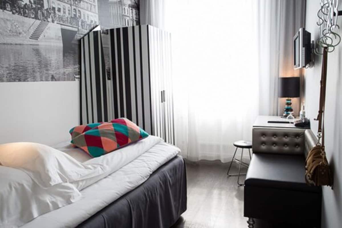 A modern bedroom with a bed, a striped wardrobe, a small desk, and a chair.