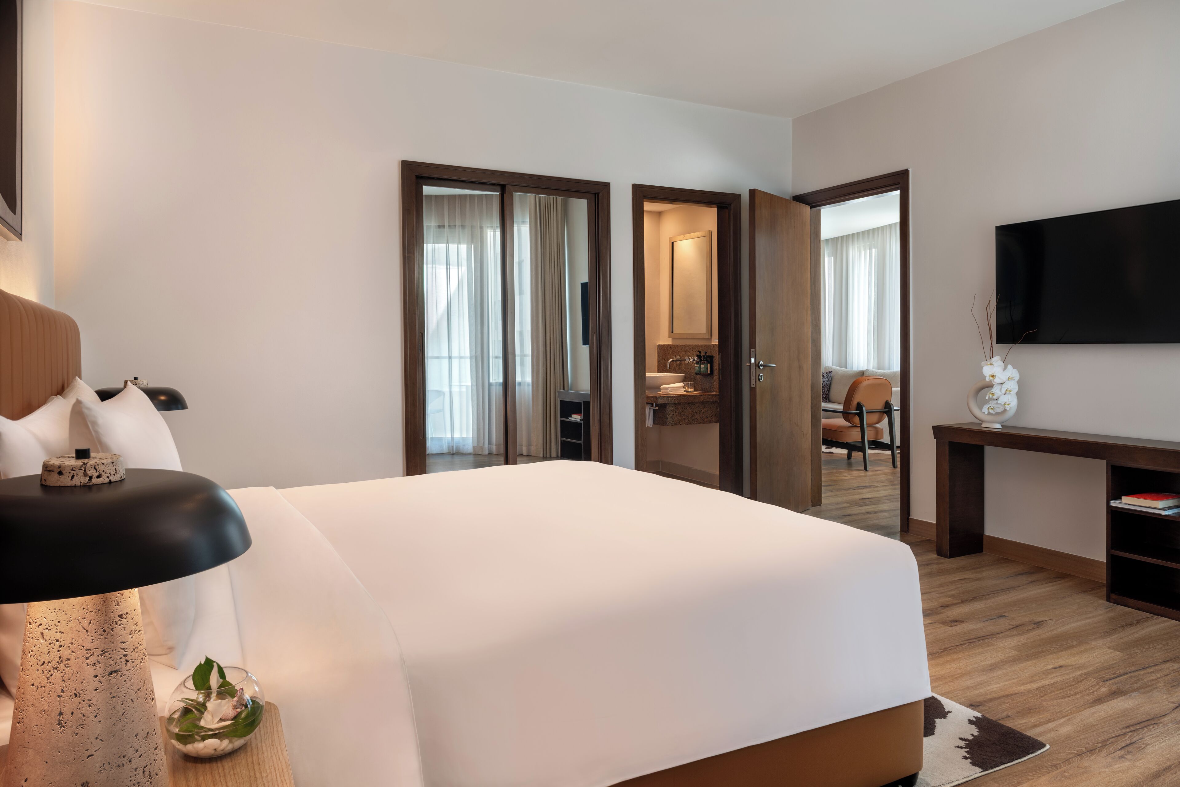 Een moderne hotelkamer met een groot bed, een bureau, een flatscreen televisie en een badkamer die door een open deur zichtbaar is.