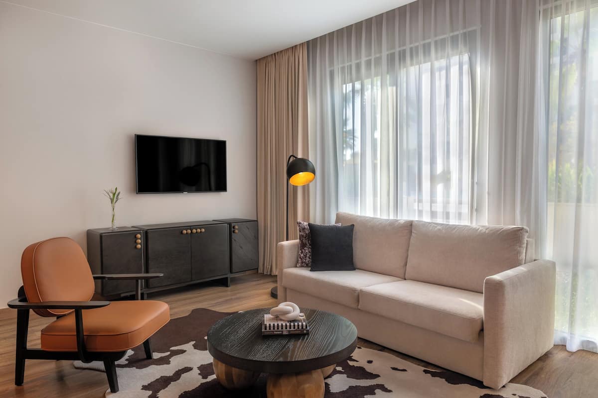 Ein modernes Wohnzimmer mit einer Couch, einem Couchtisch, einem Fernseher und einer Lampe.