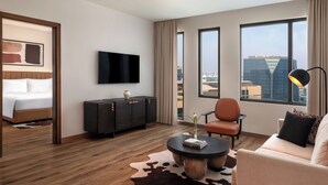 A modern hotel room with a bed, a flat-screen TV, a sofa, a coffee table, and a city view through large windows. - Staybridge Suites Abu Dhabi Yas Island by IHG (Abu Dhabi)