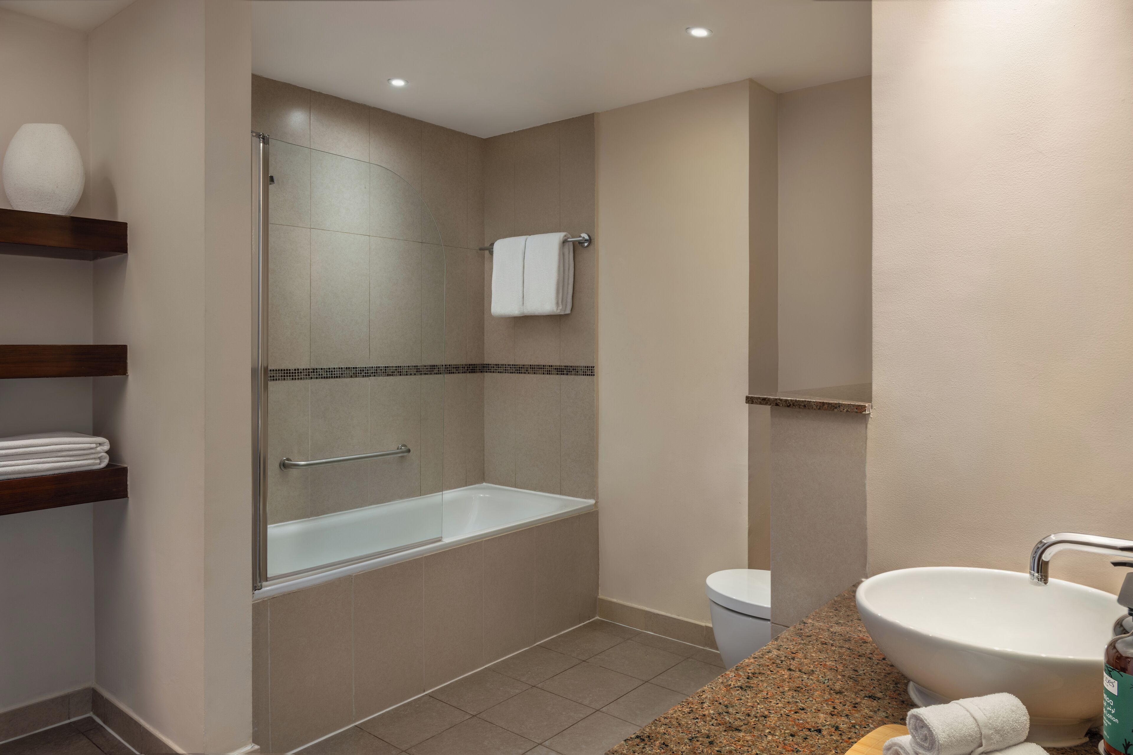 Un baño moderno con ducha de vidrio, bañera independiente, lavamanos y retrete.