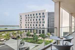 A modern hotel balcony with a view of the sea, a pool area, and a dining table. - Staybridge Suites Abu Dhabi Yas Island by IHG (Abu Dhabi)