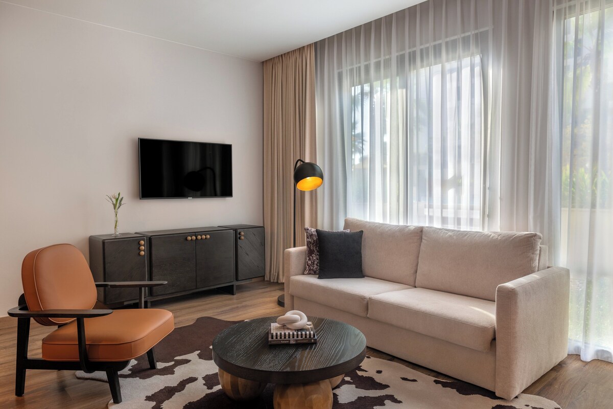 Una sala de estar moderna con un sofá, una mesa de centro, un televisor y una lámpara.