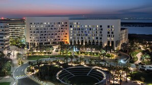 A modern hotel with a central courtyard, multiple floors, and a view of the water at dusk. - Crowne Plaza Abu Dhabi Yas Island by IHG (Abu Dhabi)