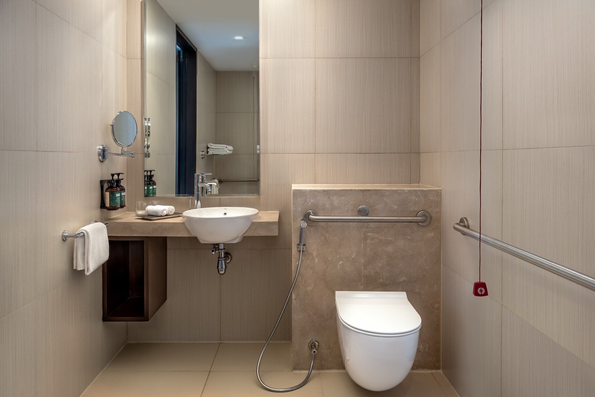 Een moderne badkamer met een wastafel, spiegel, handdoekhouder en toilet.