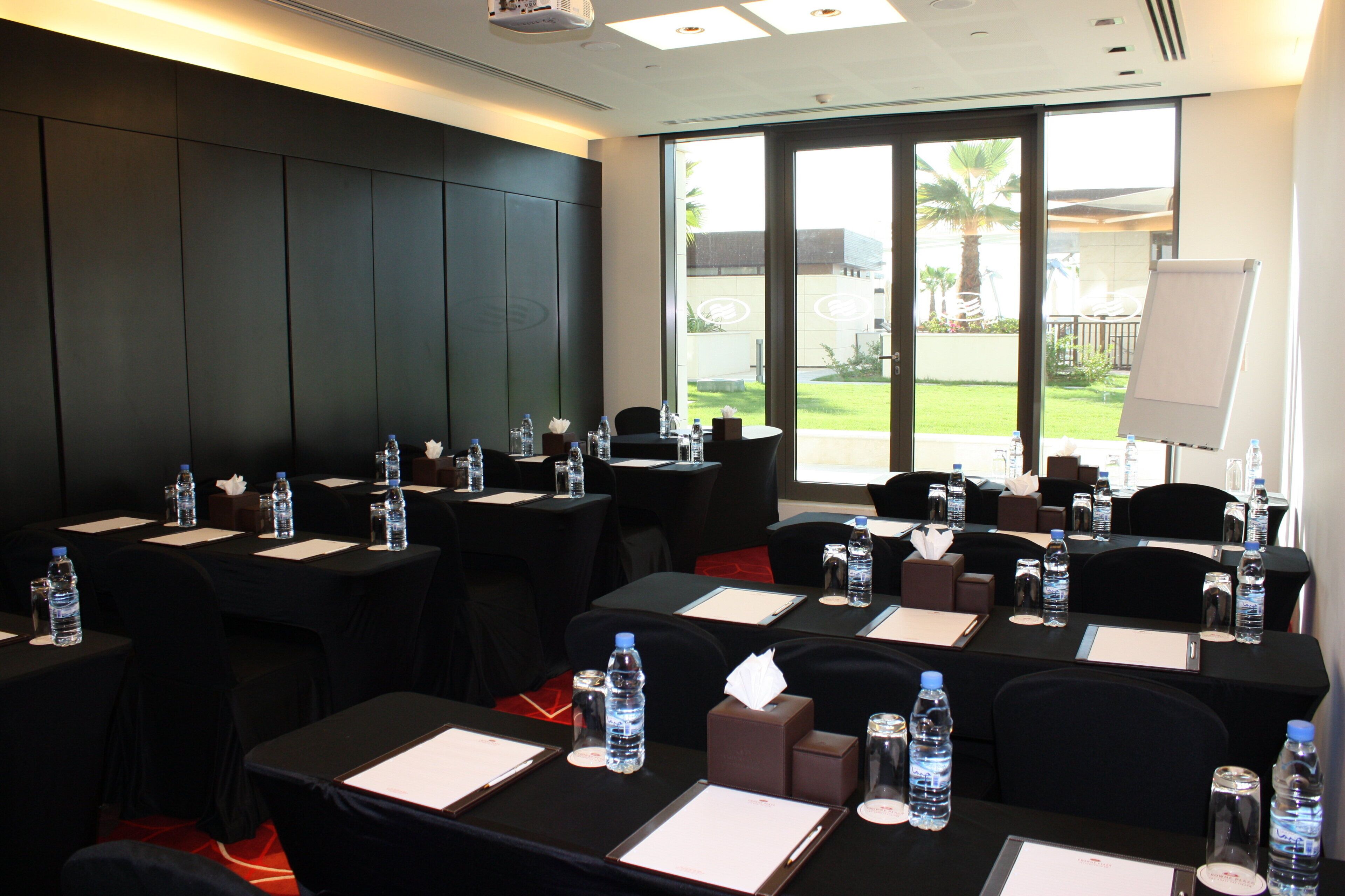 A conference room with tables set up for meetings, equipped with water bottles, notepads, and pens.