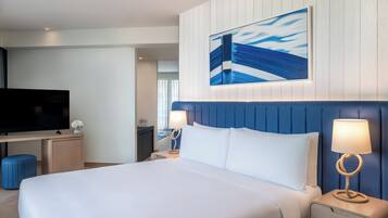 A hotel room with a large bed, a flat-screen TV, a desk, and a wall-mounted painting.