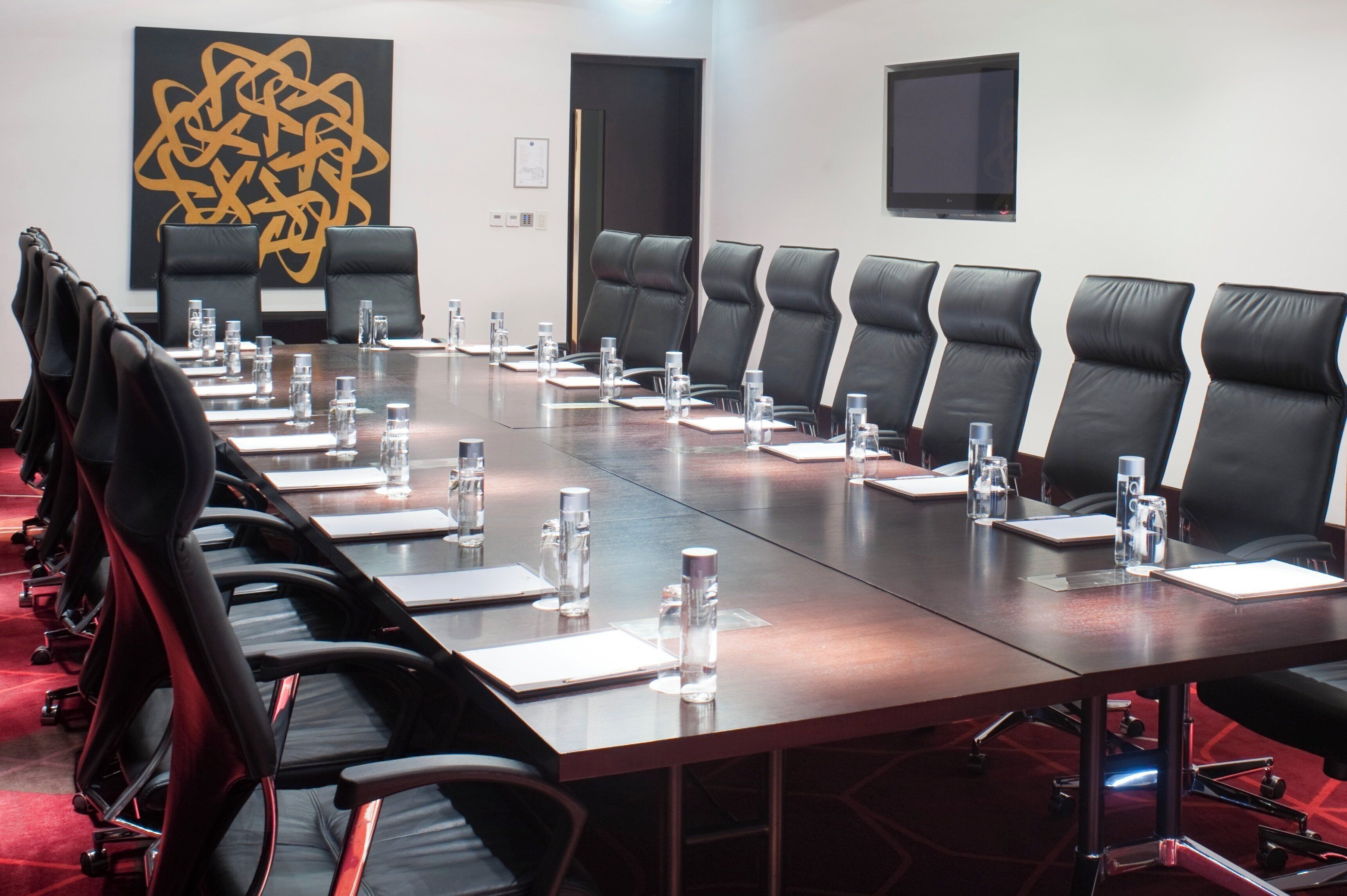 A conference room with a long table, black leather chairs, water bottles, and nameplates.