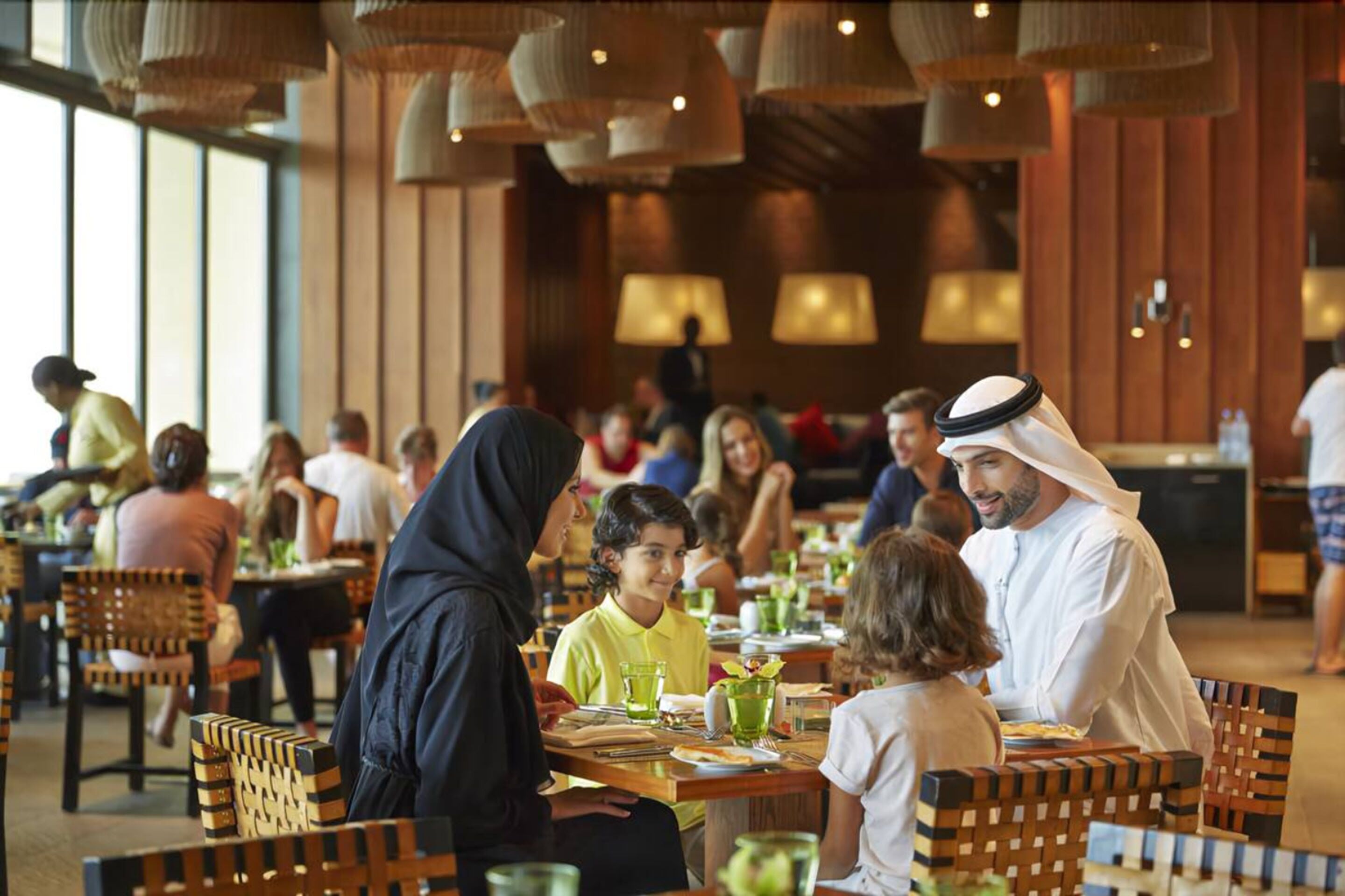 A restaurant with wooden furniture and hanging lamps.