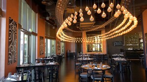 A restaurant with multiple dining tables and chairs, a bar area, and a large, circular light fixture hanging from the ceiling. - Crowne Plaza Abu Dhabi Yas Island by IHG (Abu Dhabi)