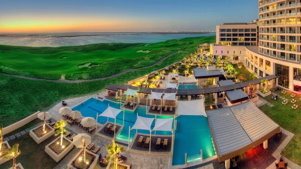 A resort with a pool area, outdoor seating, and a view of the beach and ocean. - Crowne Plaza Abu Dhabi Yas Island by IHG (Abu Dhabi)