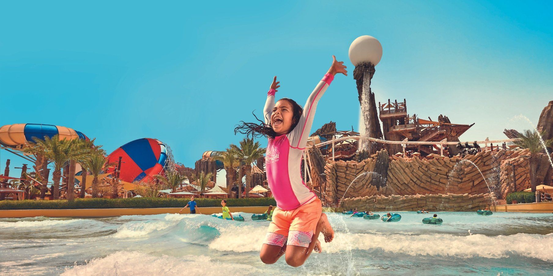 Een waterpark met een lange glijbaan, een golfslagbad en een zandstrand.
