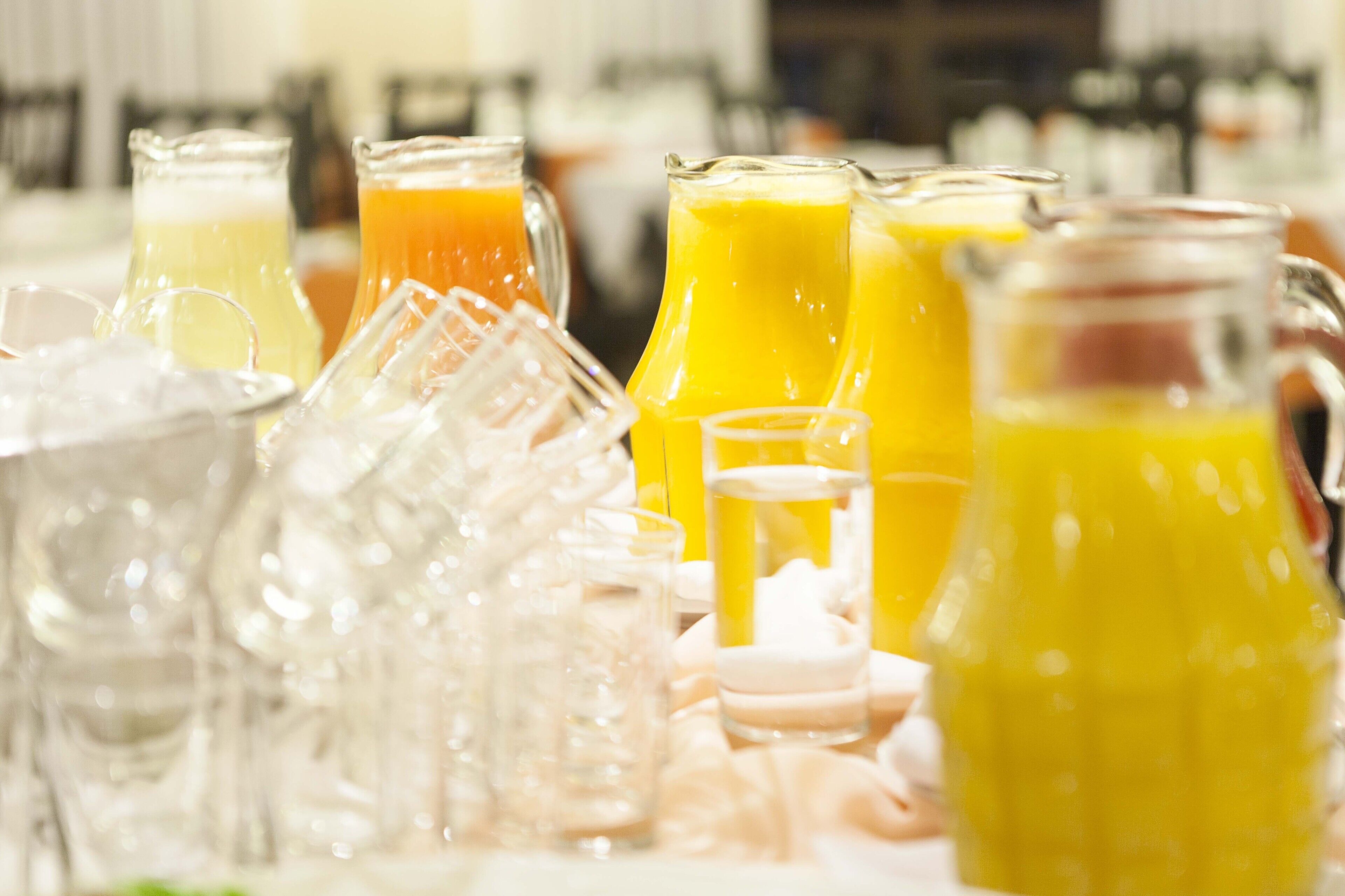 A variety of glass containers filled with orange juice, placed on a table with ice.